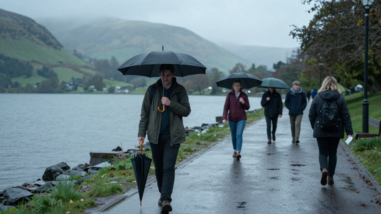 A traveler walks with an umbrella on a rainy pavement in the Lake District.